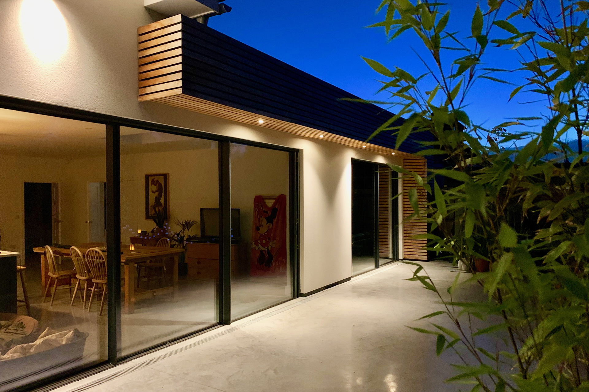 Externally, white render, timber cladding and aluminium glazing give the house a lighter and more contemporary presence.
