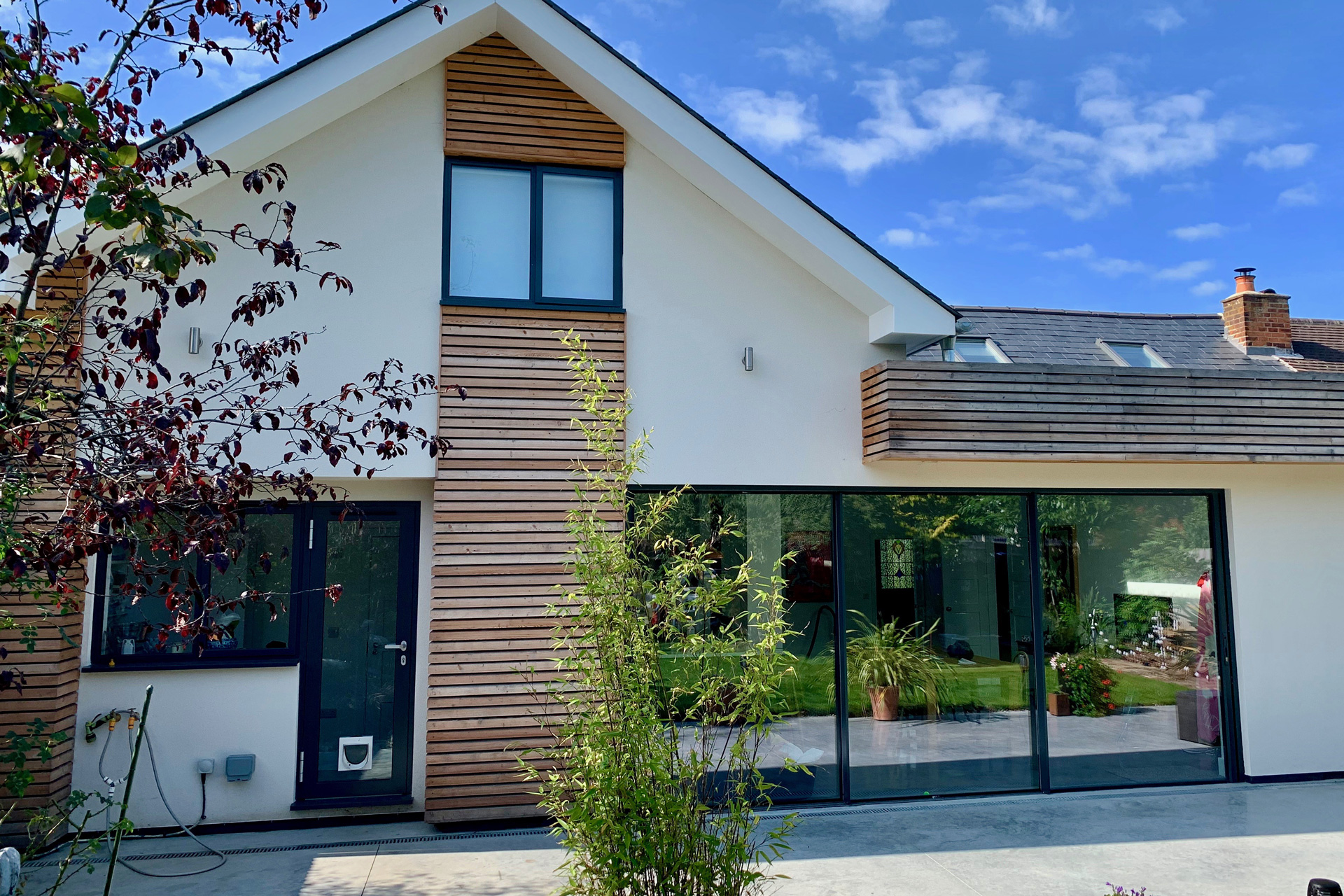 Externally, white render, timber cladding and aluminium glazing give the house a lighter and more contemporary presence. The redesign brings clarity and openness to the home, creating a more practical layout suited to modern family living.