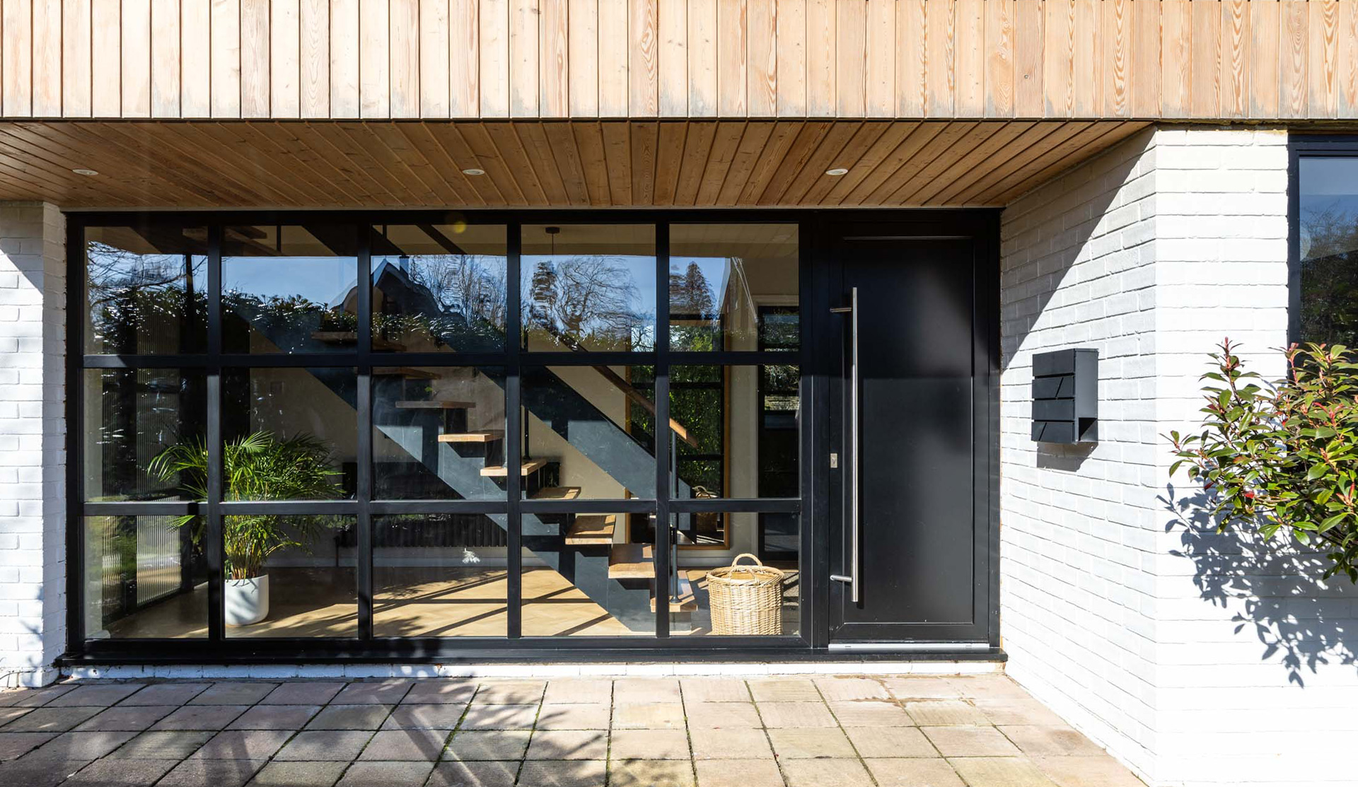 Externally, natural larch cladding, white render and standing seam metal detailing introduce a restrained contemporary material palette that contrasts against the original building form while maintaining a cohesive overall composition.