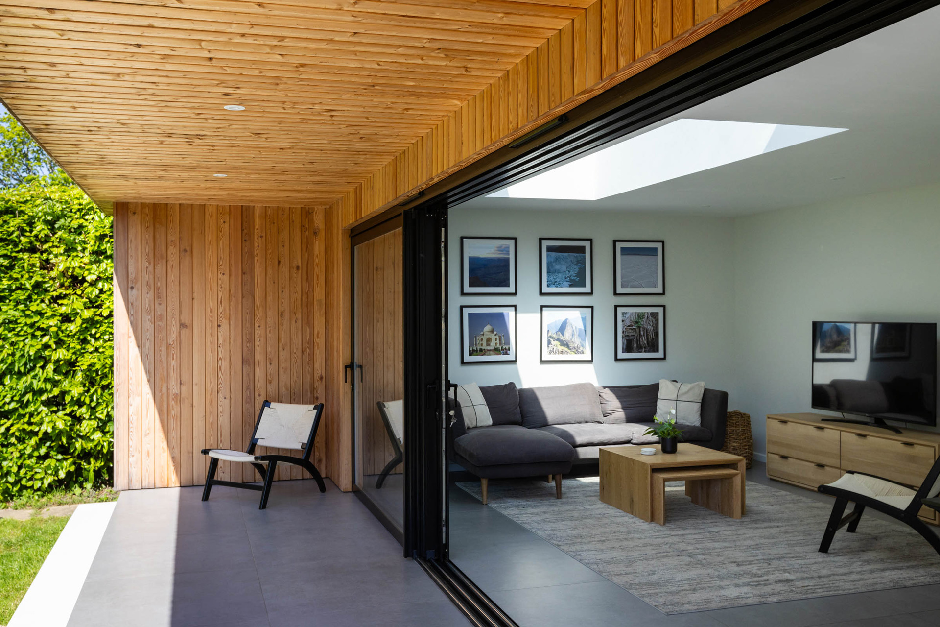 Externally, natural larch cladding, white render and standing seam metal detailing introduce a restrained contemporary material palette that contrasts against the original building form while maintaining a cohesive overall composition.