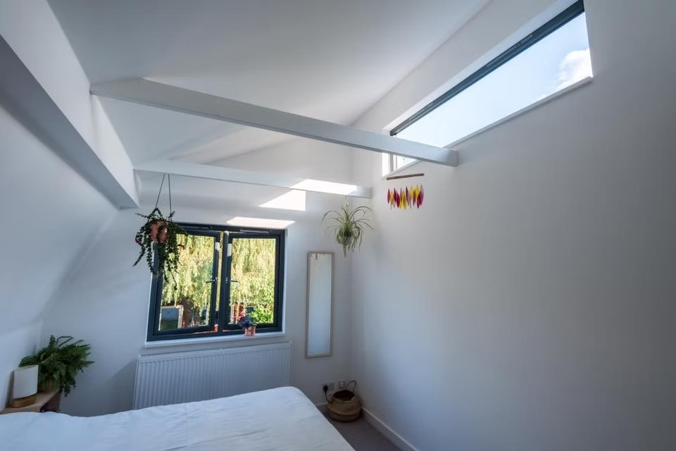Rooflights and carefully positioned glazing bring natural light deep into the house, with exposed structural elements helping define the upper rooms and vaulted ceilings.