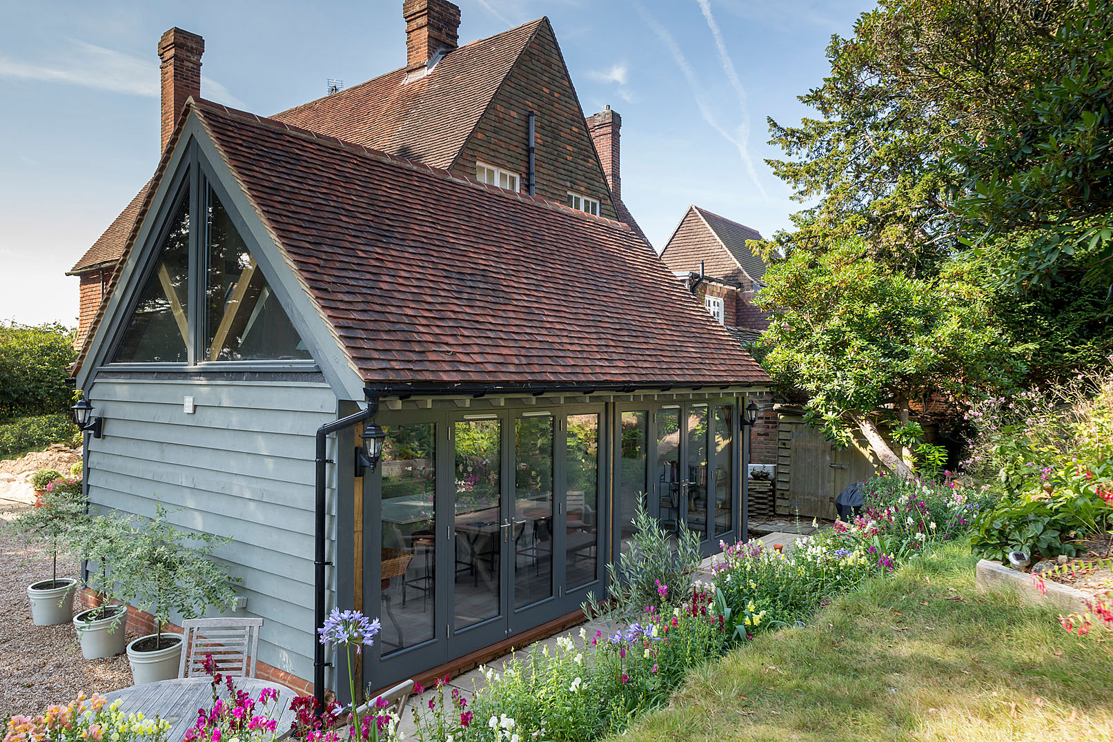 The design introduces a carefully considered oak-framed kitchen extension positioned to make the most of the surrounding gardens.
