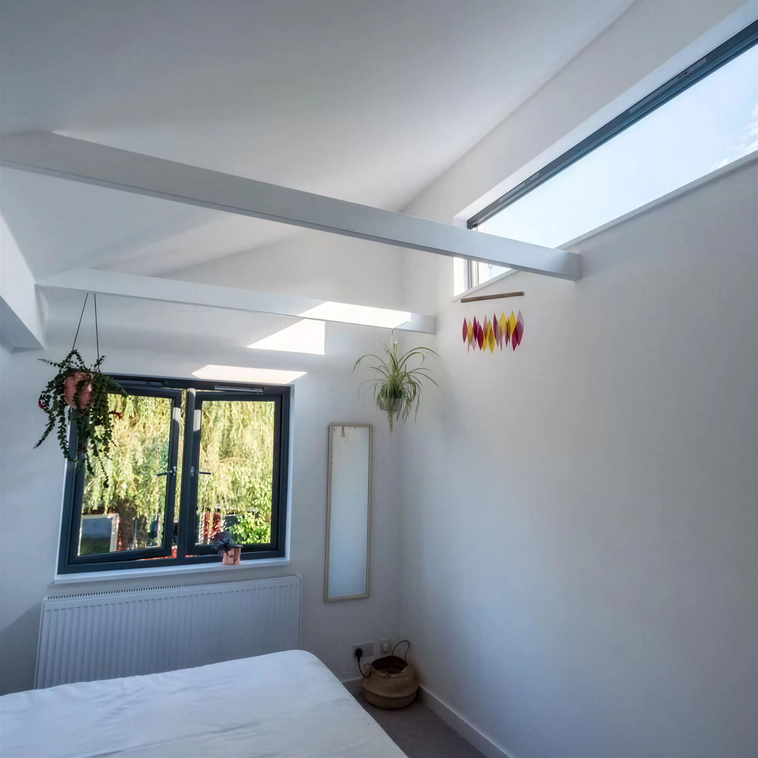 Vaulted bedroom inside a Dutch barn-style home featuring exposed ceiling beams, rooflights and modern architectural detailing.