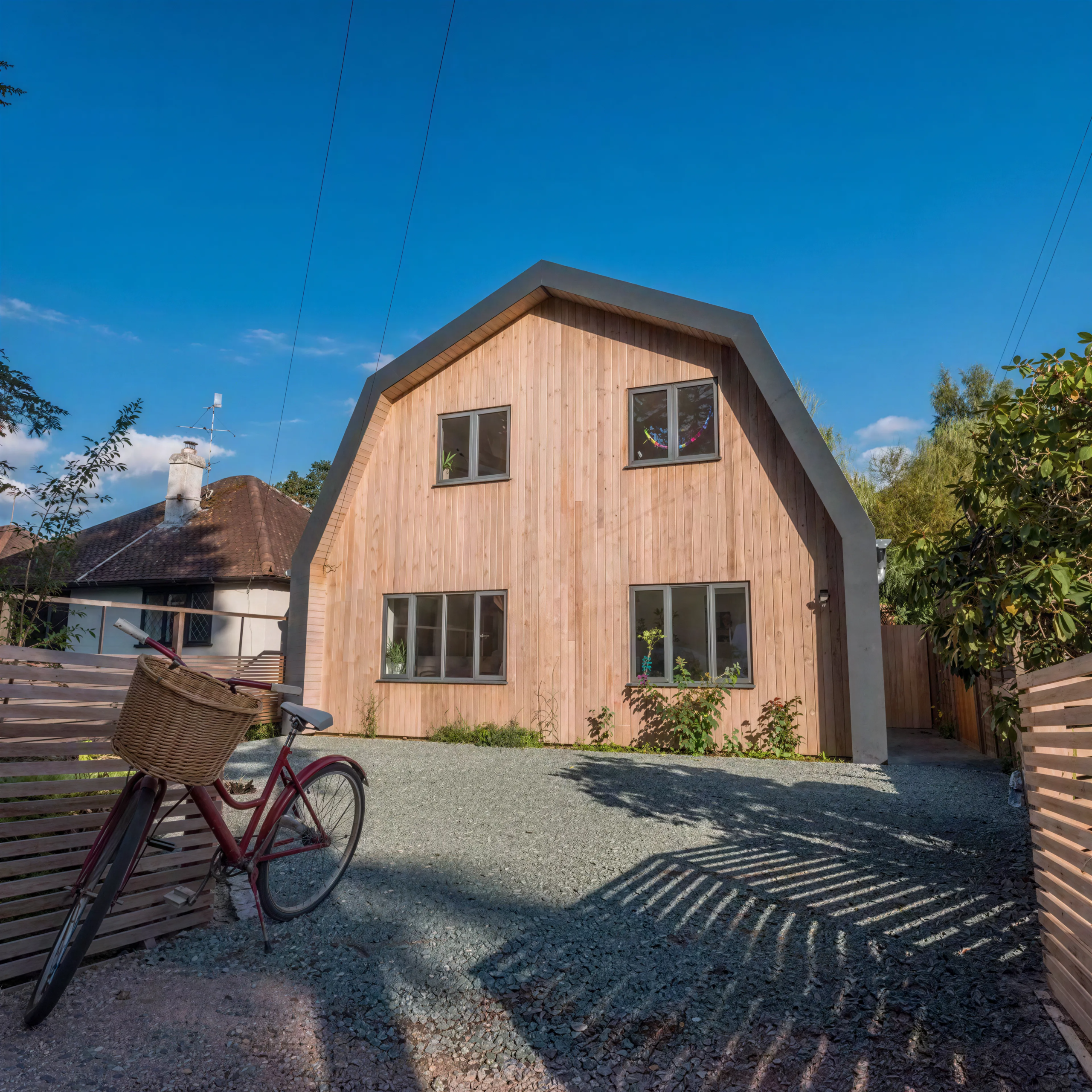 Modern Dutch barn-style house with natural larch cladding, aluminium roof detailing and contemporary architectural design.